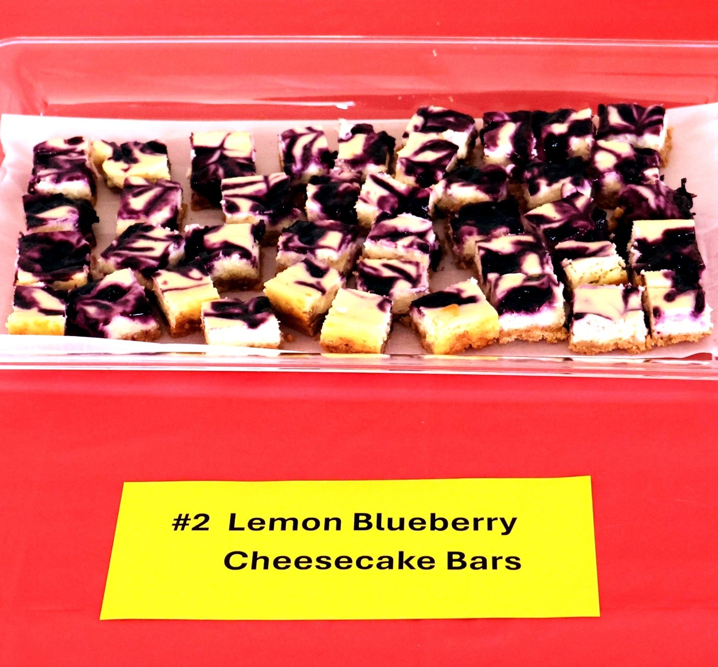 Image of lemon blueberry cheesecake bars on a red tablecloth